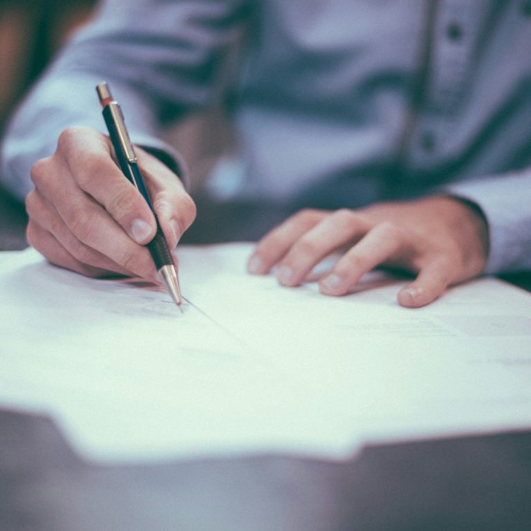 Mano firmando declaración fiscal como parte del servicio de presentación de impuestos y asesoría tributaria